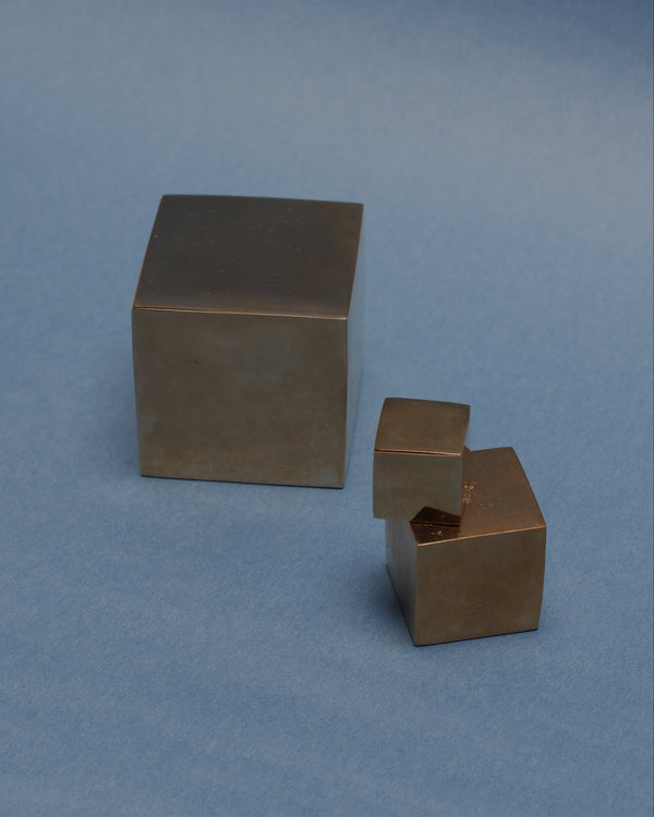 Three bronze cubes of different sizes on a blue background