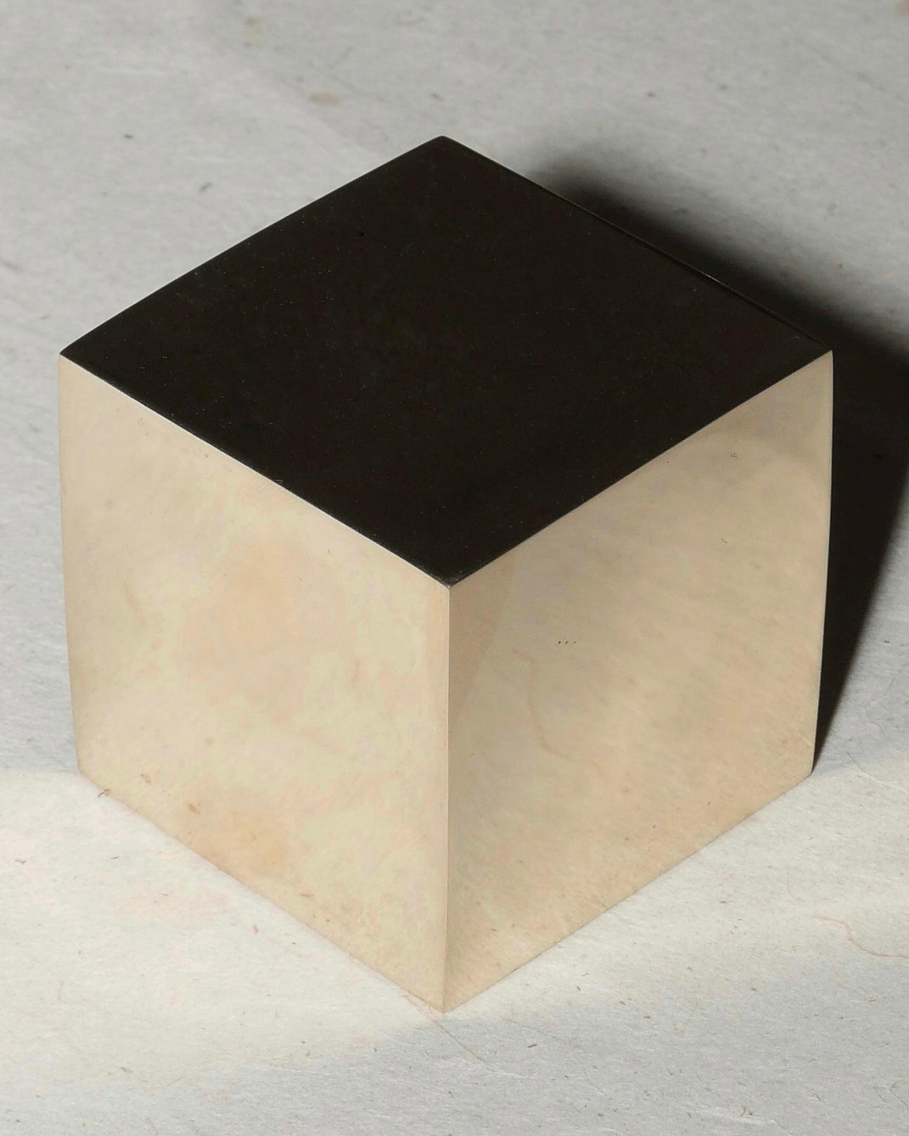 Two-tone cube with black top and beige bottom on a textured surface